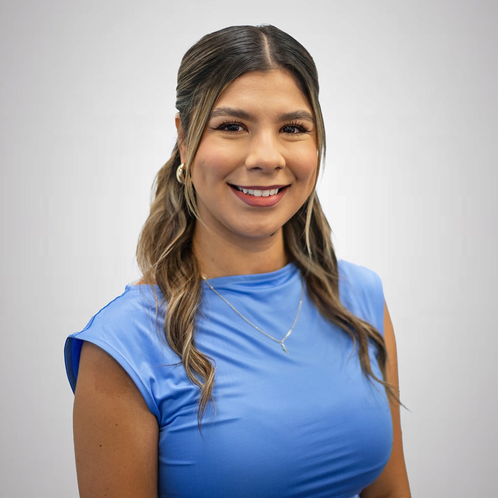 Jaxmin Ramirez a young Hispanic woman with long brownish blonde hair wearing a blue short sleeve shirt and smiling into the camera