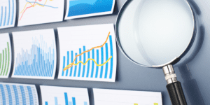 Several charts and graphics in blue and orange next to a magnifying glass