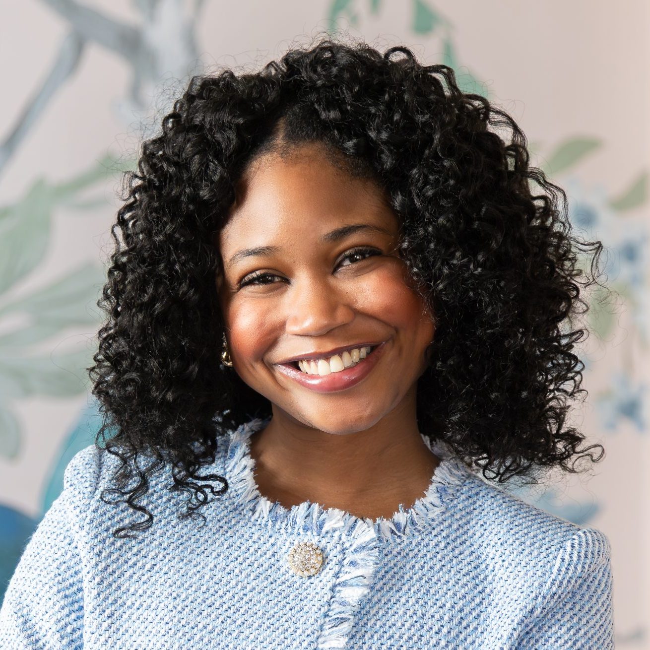 DeAndra Bolden a Black woman with short curly hair wearing a light blue jacket and smiling into the camera