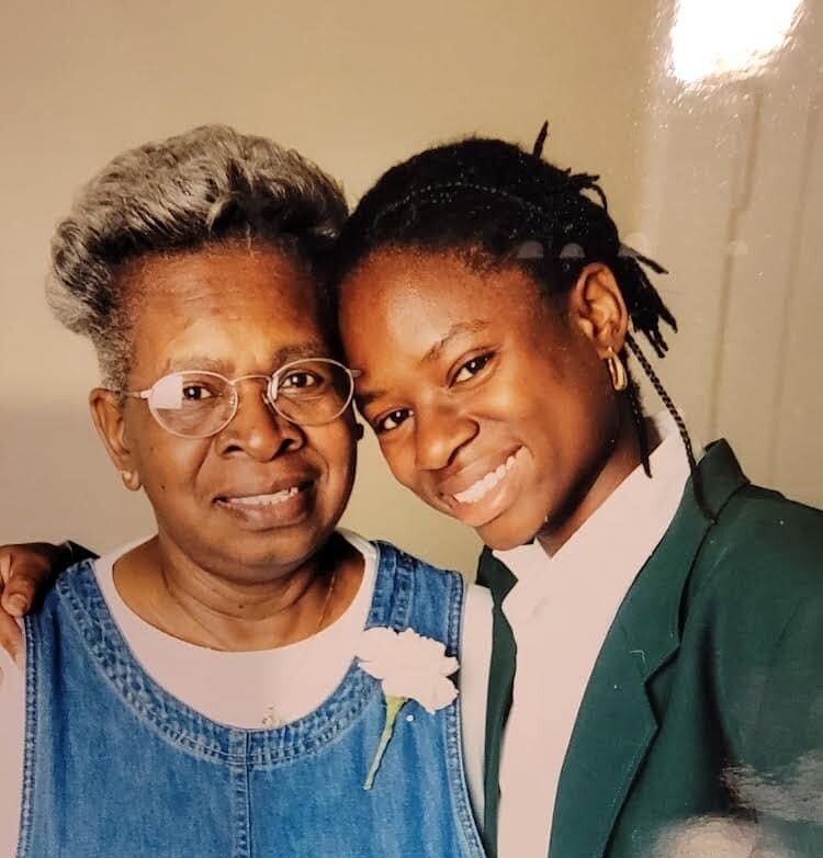 Jamiel, a Black woman, with her grandmother smiling into the camera