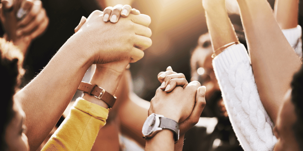 Hands of diverse people in the air some of them clasped