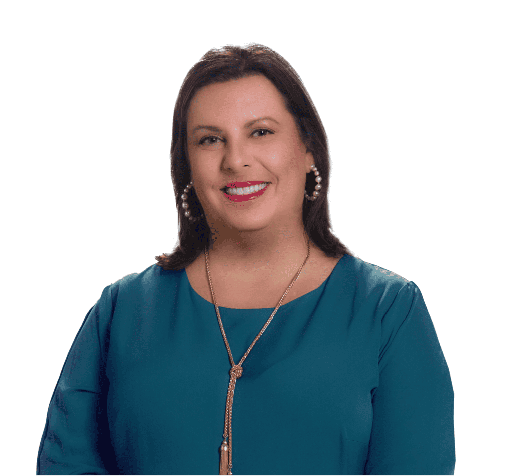 A white woman with shoulder-length brown hair wearing a blue top and gold necklace