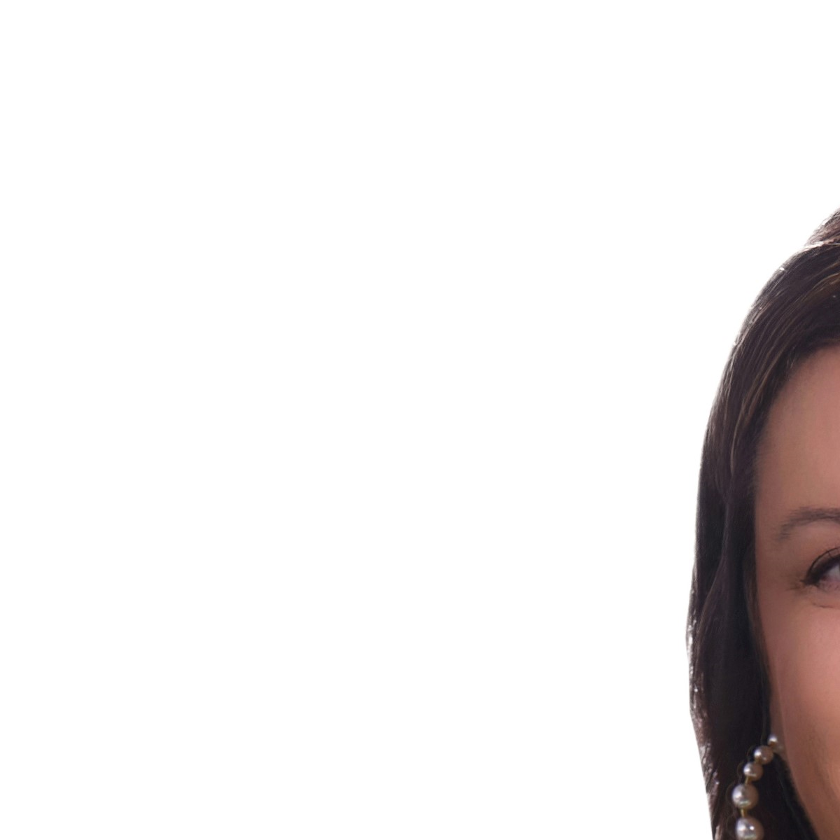 A white woman with shoulder-length brown hair wearing a blue top and gold necklace