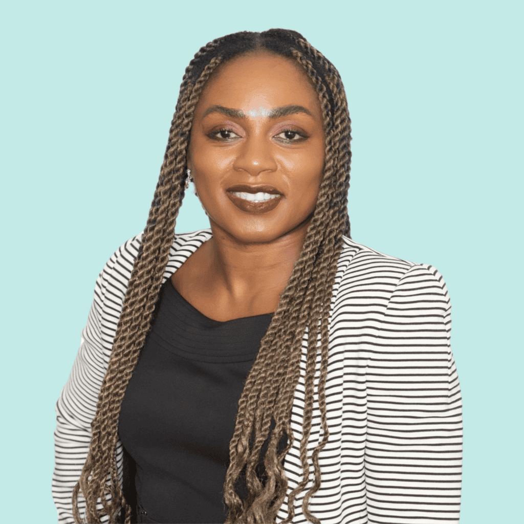 Photo of Kadian Douglas, a Black Dominican woman with long dark hair wearing a black and white striped jacket, smiling into the camera