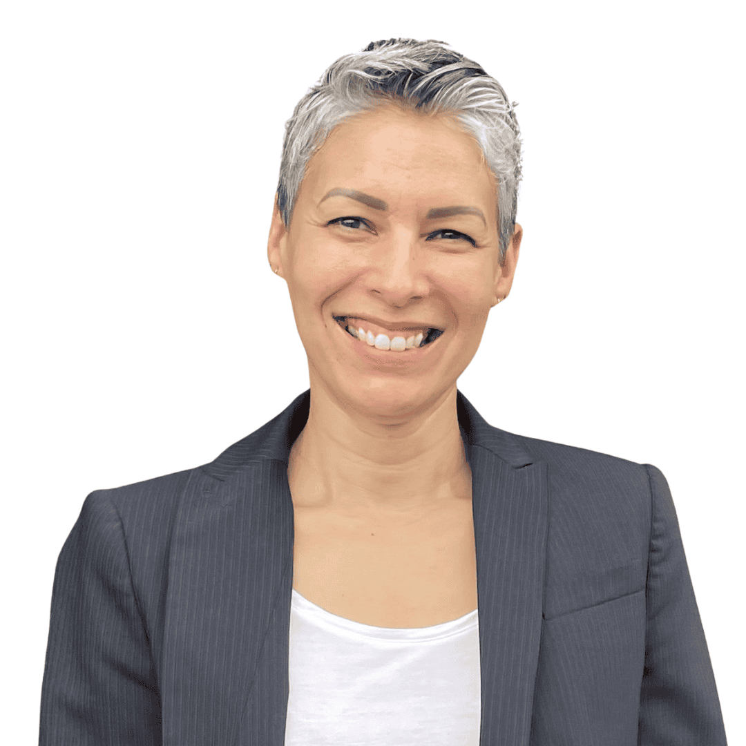 Photo of Meriel Martínez, a Puerto Rican woman with grey cropped hair wearing a grey jacket and white top