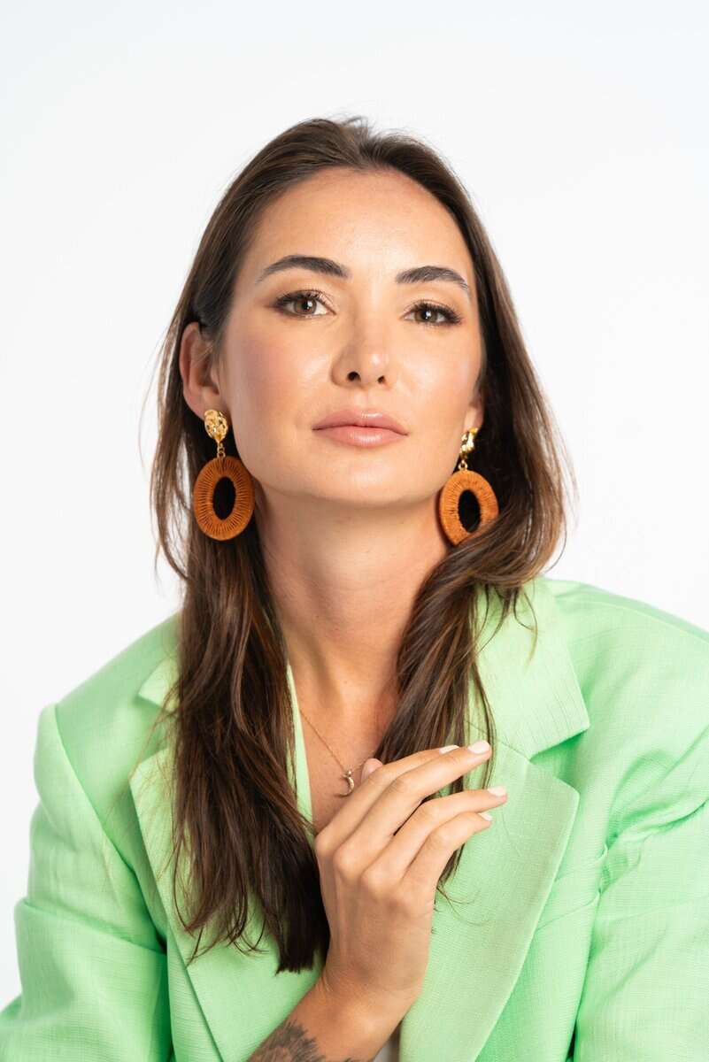Headshot of Sam Rad a white woman with long brown hair wearing a lime green jacket and large brown hoop earrings