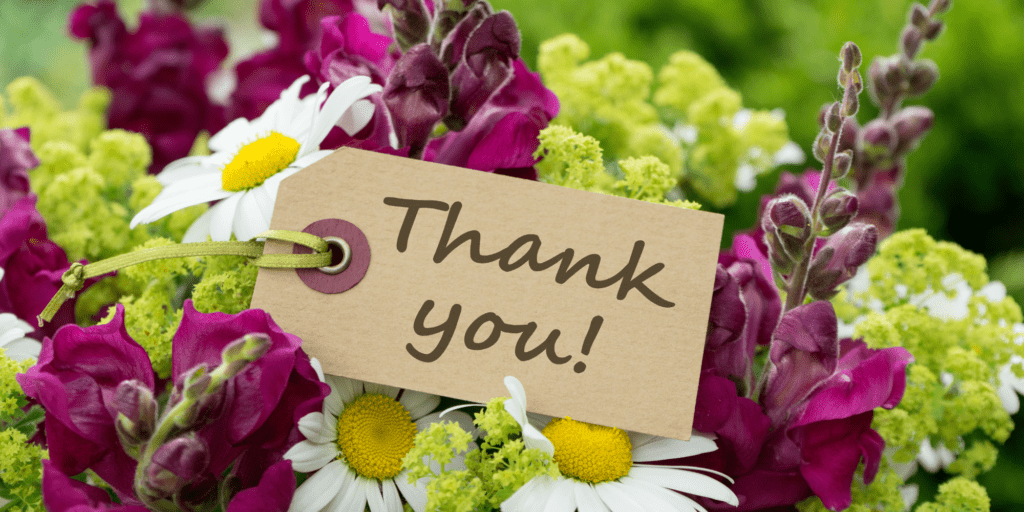 Bouquet of white, purple and green flowers with a brown tag that says thank you!