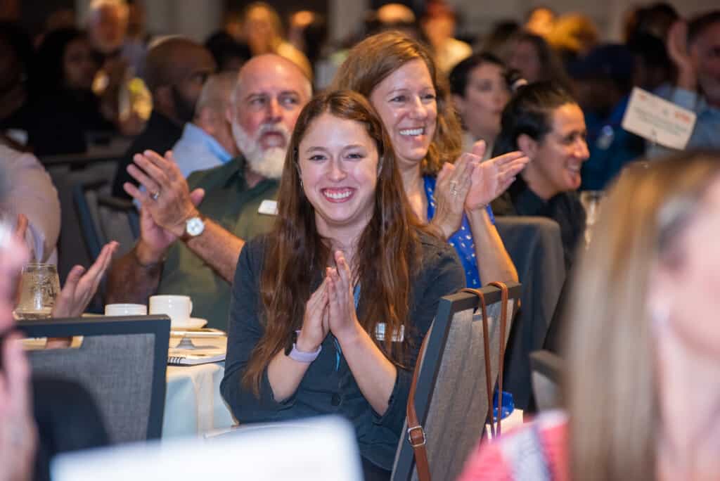 White woman with red hair clapping in a crowd at the Nonprofit Leadership Center conference