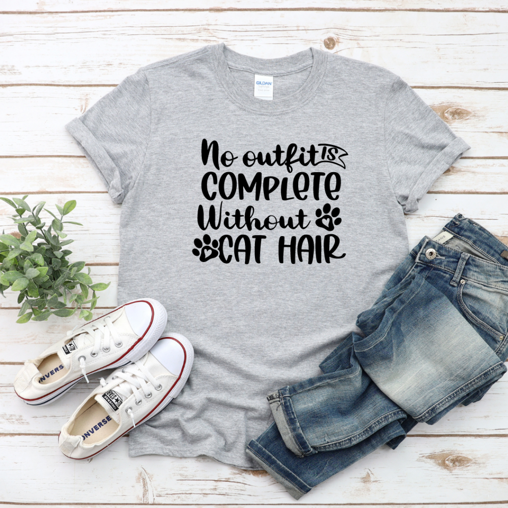 Grey T-shirt that says "no outfit is complete without cat hair" in black type